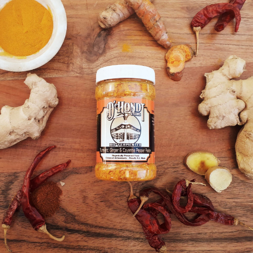 Bio-fermented turmeric, ginger, and cayenne chili pepper paste in a jar, highlighting vibrant orange and red hues with organic ingredients and bio-fermented turmeric and ginger sea salt